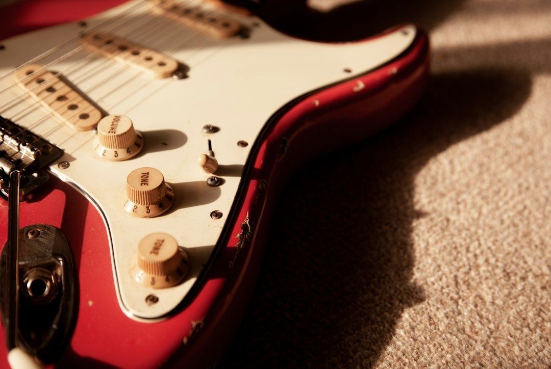 Nahaufnahme einer roten E-Gitarre mit Reglern und Tremolo-Bereich